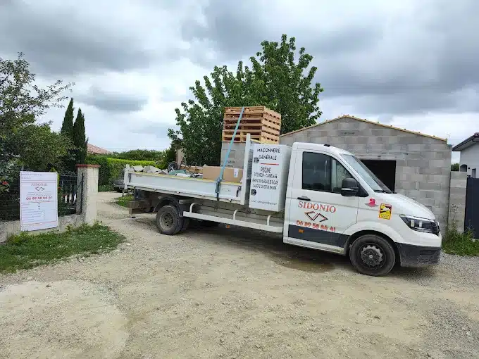 Camion Sidonio blanc chargeant matériaux sur un chantier. Entreprise de maçonnerie générale, piscine, extension. Tél: 06 89 58 66 41.