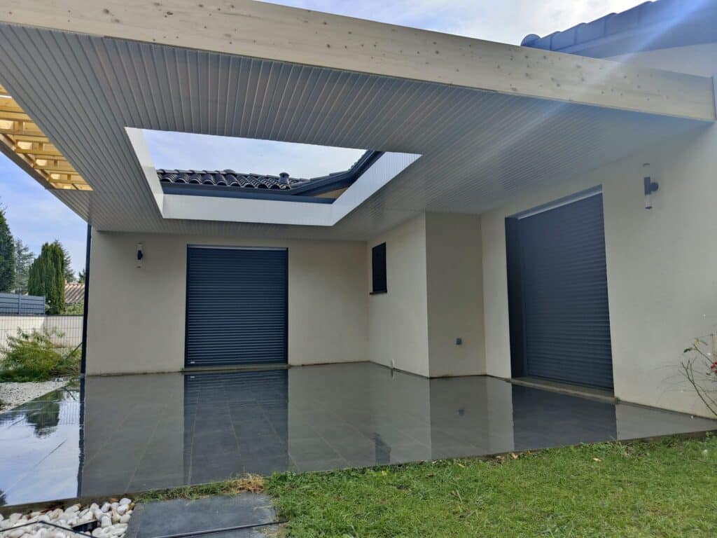 Terrasse moderne couverte avec lames de plafond et puits de lumière, sol carrelé noir réfléchissant, volets roulants gris.