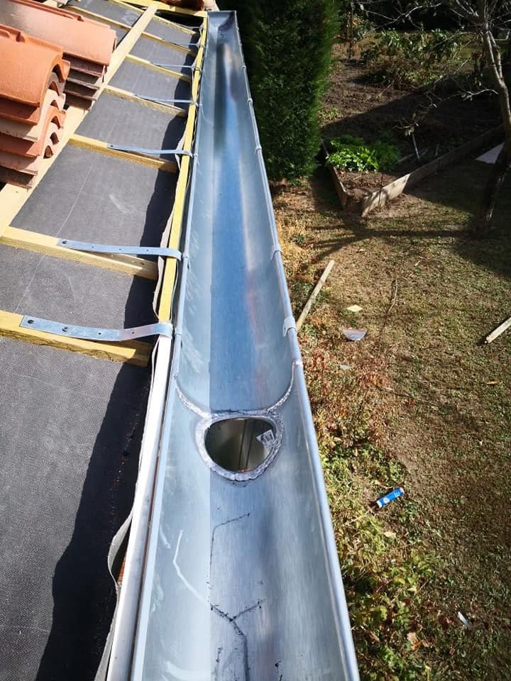 Gouttière en zinc neuve installée sur une toiture en cours de couverture, avec sortie de descente raccordée.